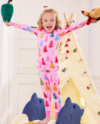 Child standing with arms raised and plush toys in the Pastel Christmas pajama set.