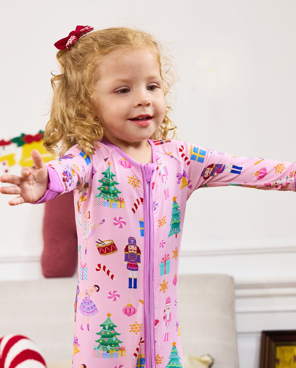 Close view of a child with arms out in the Pink Nutcracker zip-up romper.