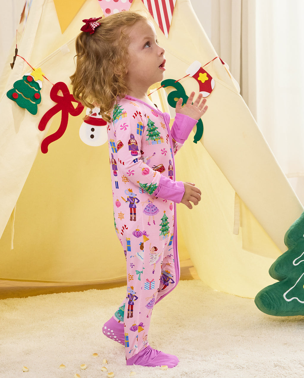 Side view of a child standing with a toy in the Pink Nutcracker romper.