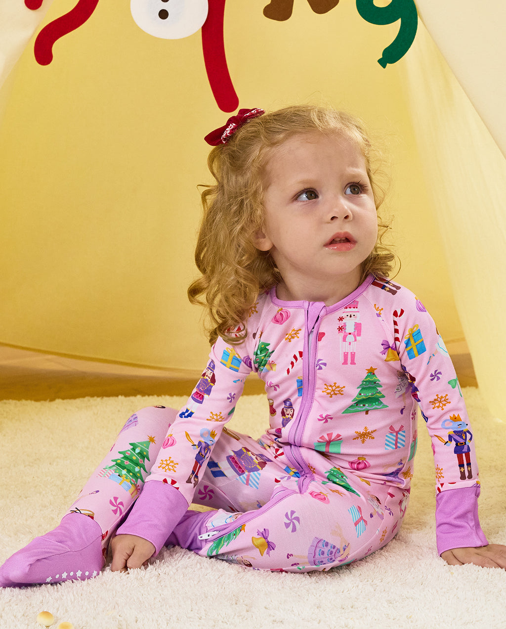 Child seated on a rug in the Pink Nutcracker zip-up romper.