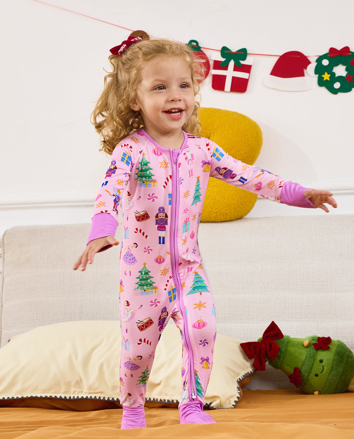 Child standing on a sofa with a hand extended in the Pink Nutcracker romper.