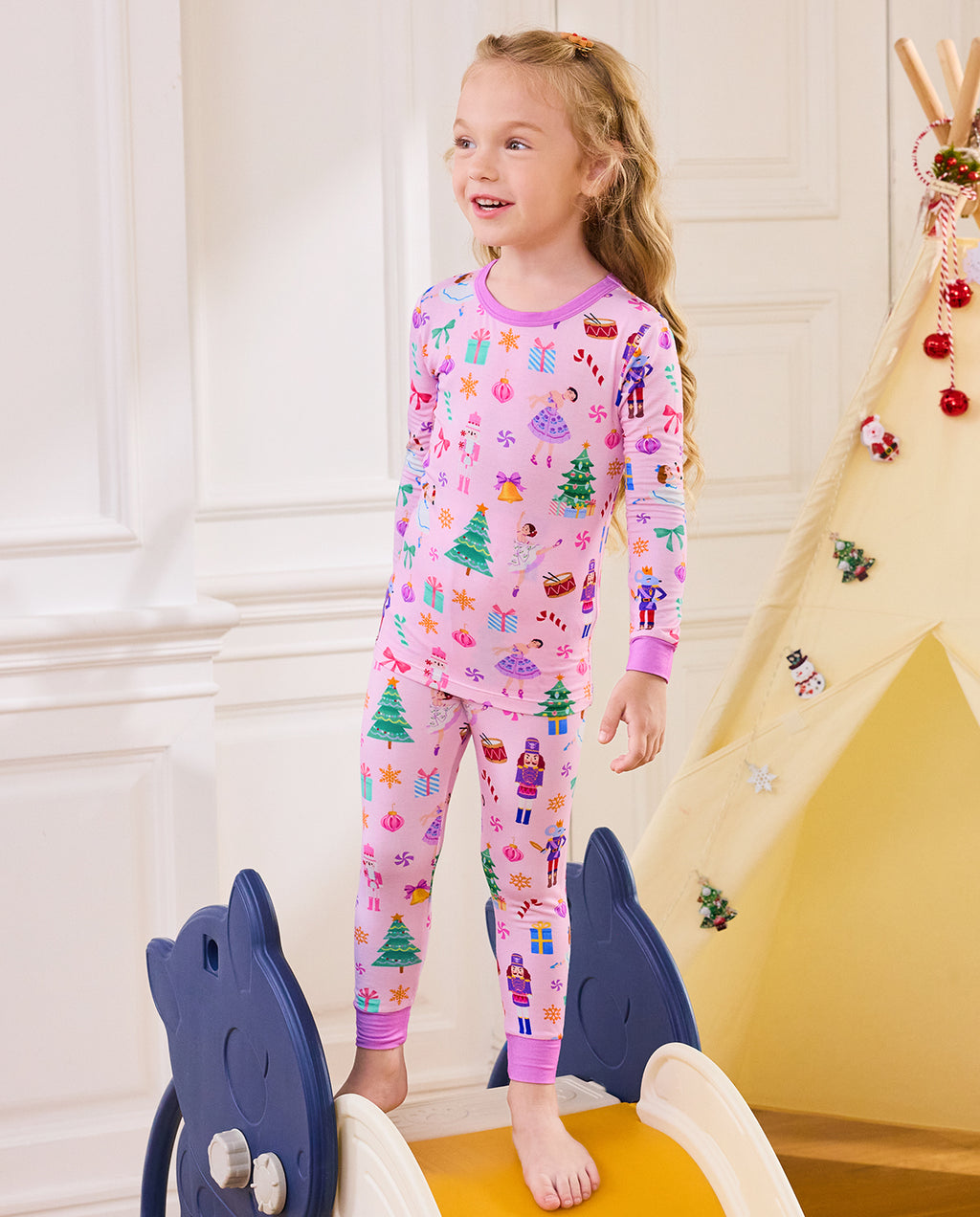 Child standing on a slide in the pink Pink Nutcracker two-piece set.