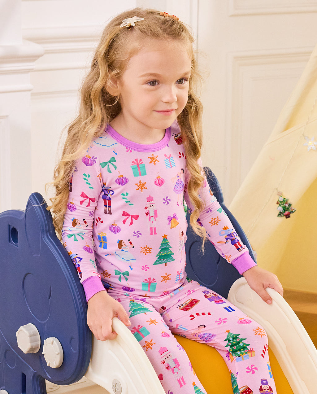 Close view of a child seated on a slide in the Pink Nutcracker top.