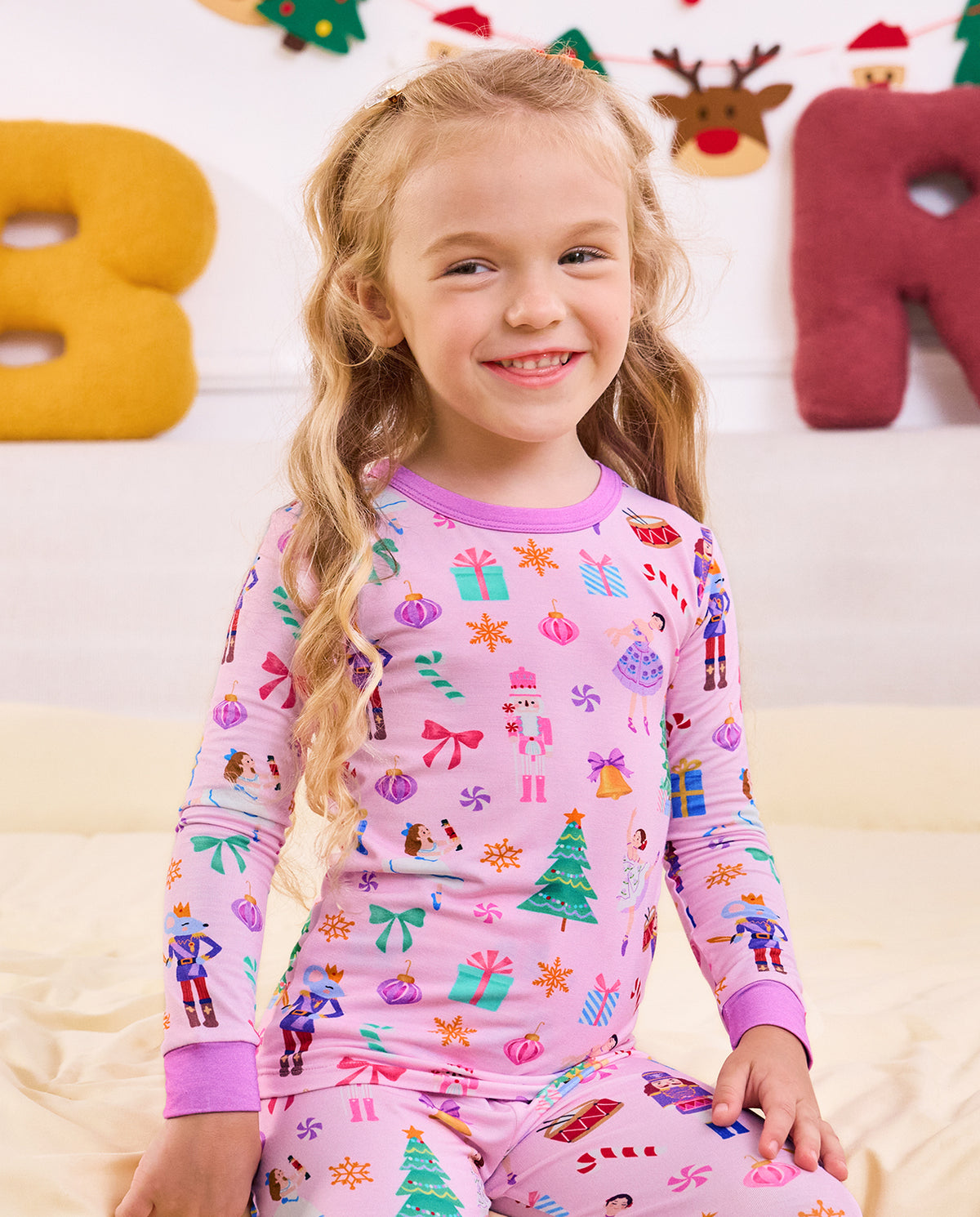 Child seated on a sofa in the pink Pink Nutcracker pajama set.