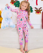 Child holding a blue unicorn plush while seated in Pink Nutcracker pajamas.