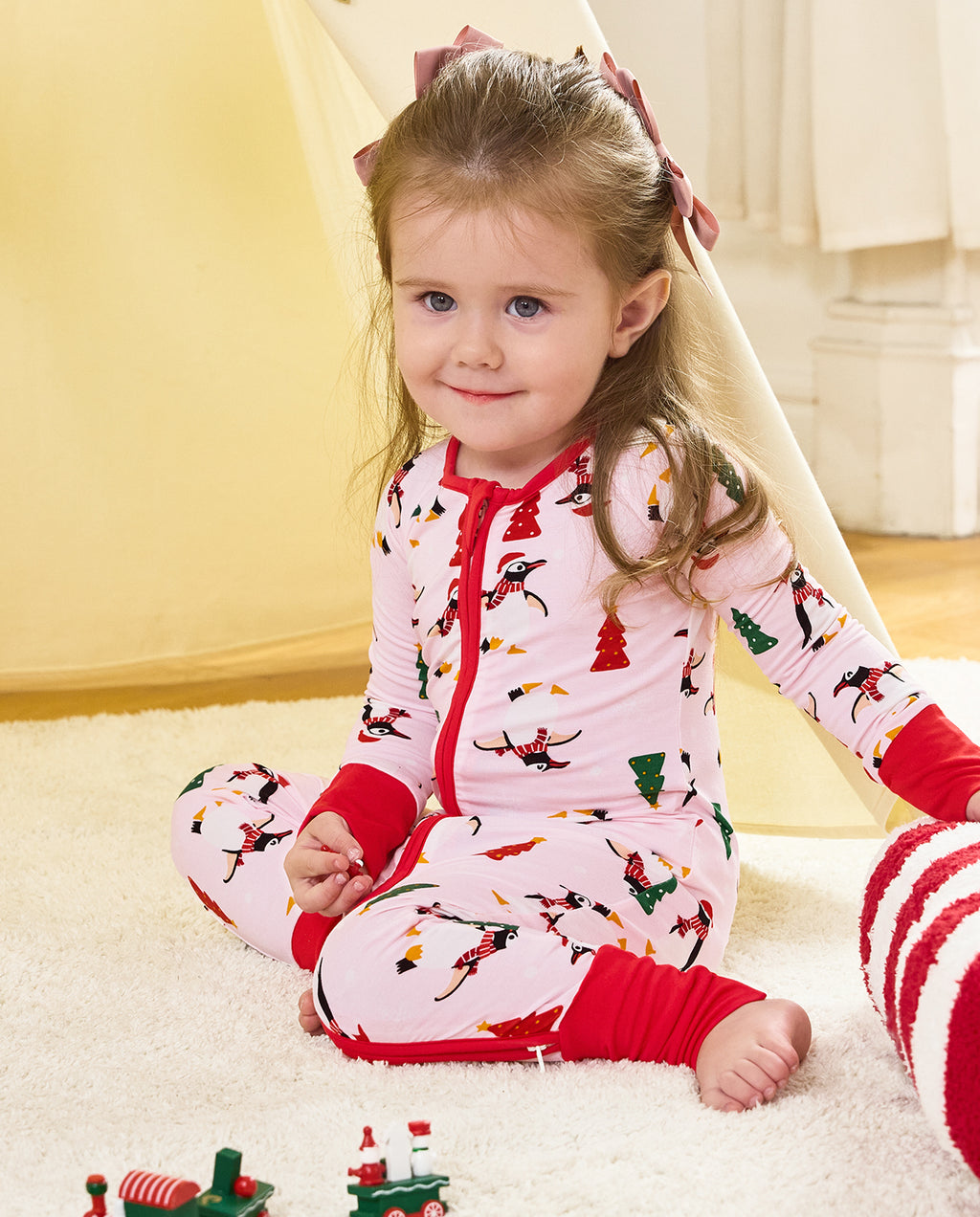 Child seated on a rug in the Pink Penguins romper with red cuffs.