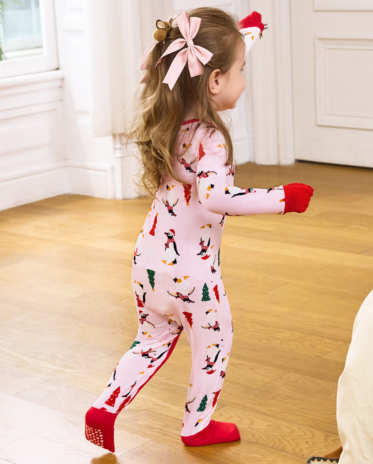 Rear view of a child standing in the pale pink Pink Penguins romper.