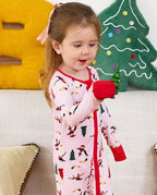 Child holding a small toy while standing in the Pink Penguins zip-up romper.