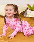 Child crawling on bedding in the pink Pumpkin Bows zip-up romper.