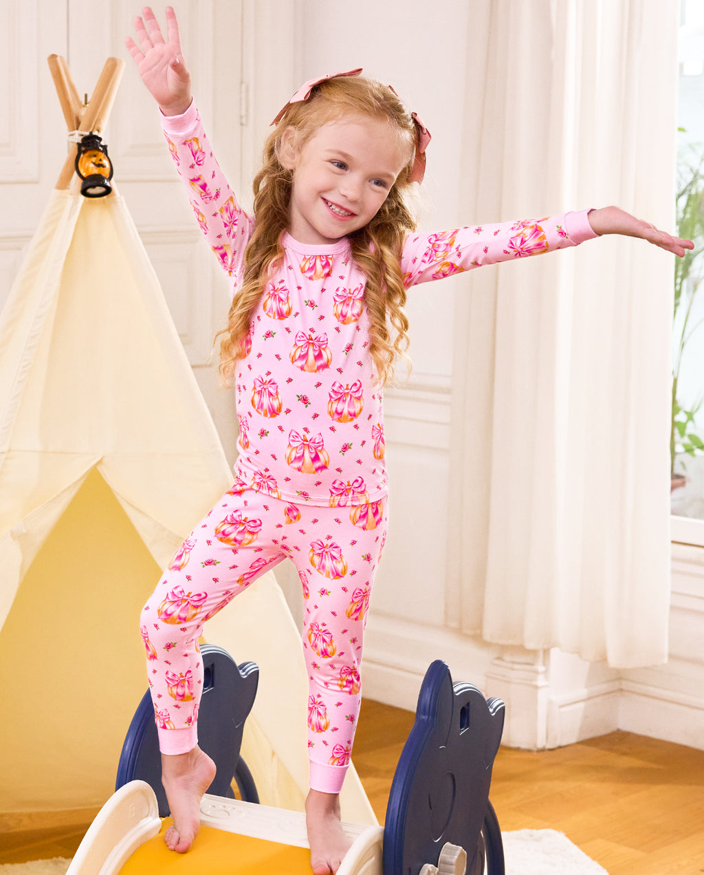 Child standing with arms out in pink Pumpkin Bows pajamas.