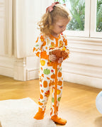 Child standing and holding a pinecone toy in the Pumpkin Patch zip-up romper.