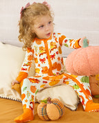 Child seated on a sofa with a plush pumpkin, wearing the Pumpkin Patch romper.