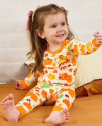 Child seated on a sofa and looking upward in the Pumpkin Patch pajama set.