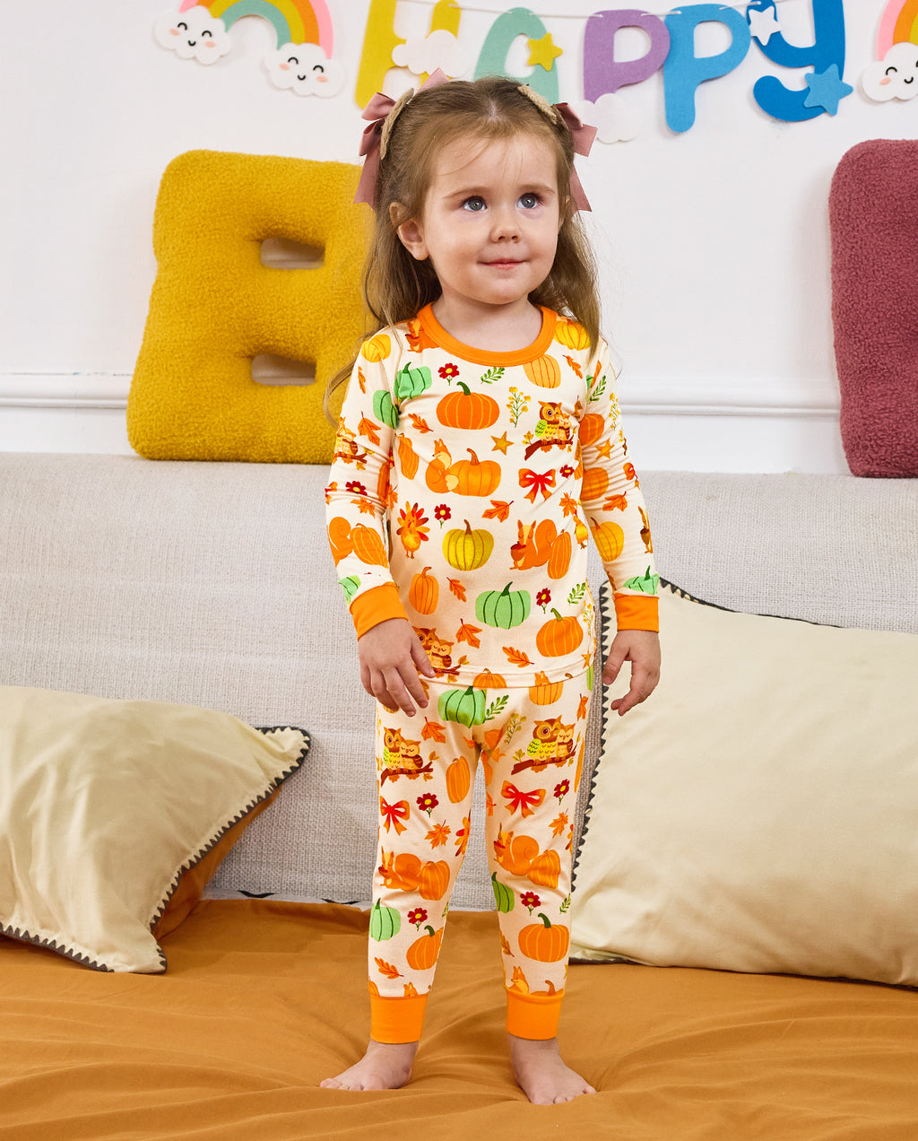 Child standing on a sofa in Pumpkin Patch long-sleeve pajamas.