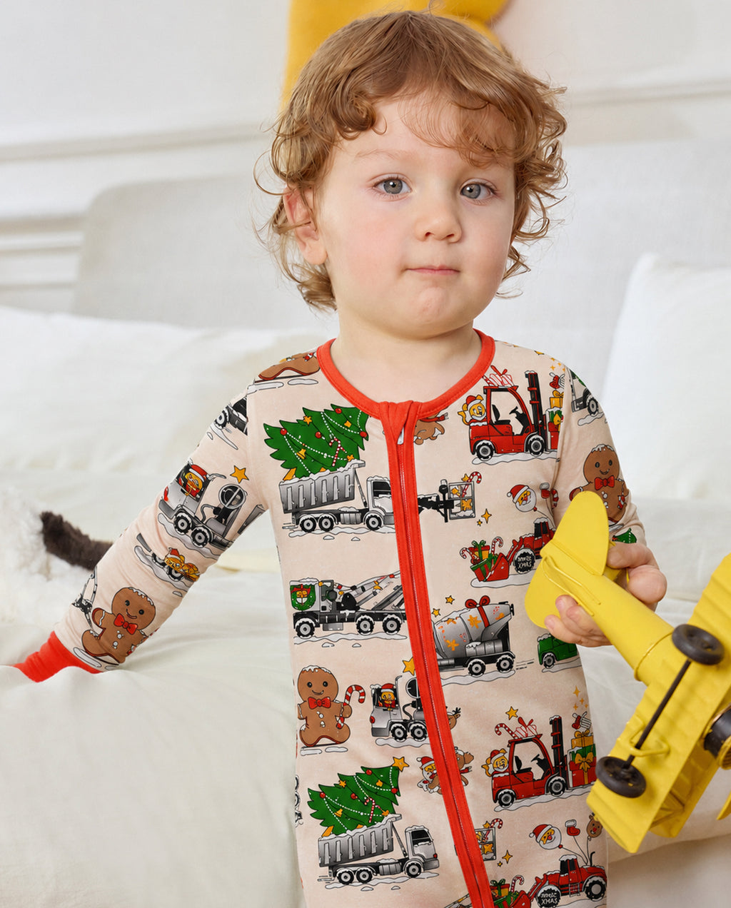 Child standing in Santa Express cream vehicle-print zippy with red trim and holding a yellow toy