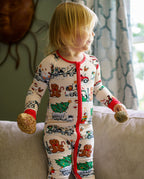 Child standing on a sofa in Santa Express zippy while holding round ornaments