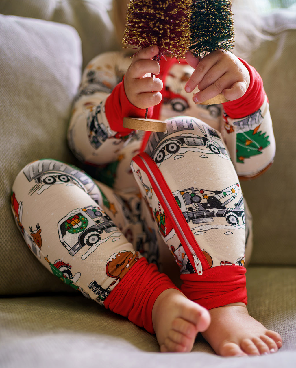 Child seated in Santa Express zippy with open foot cuffs while holding small decorative trees