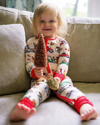 Smiling child sitting on a sofa in Santa Express zippy and holding a decorative tree