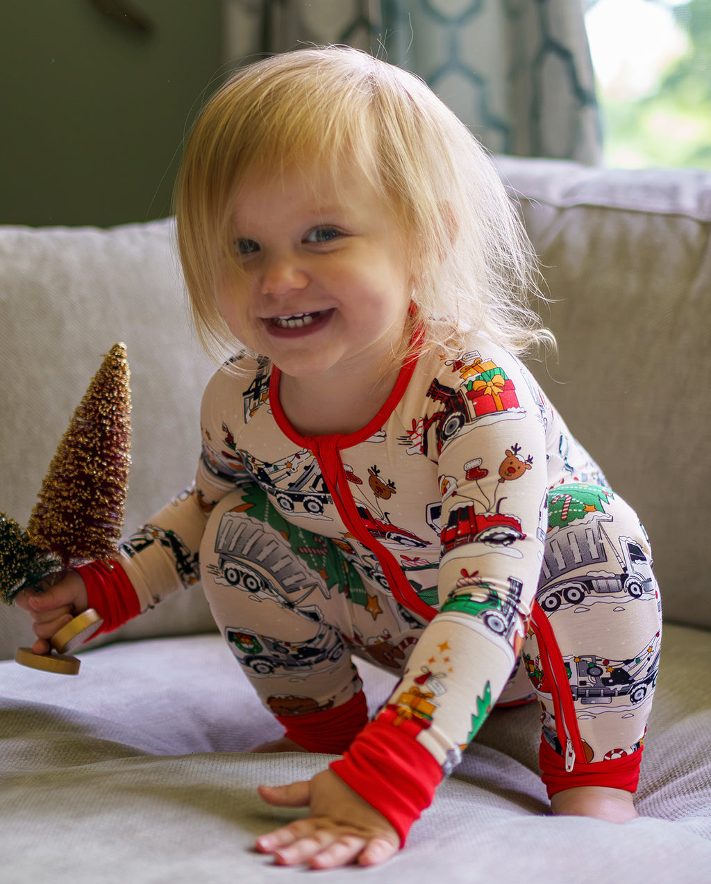 Child leaning forward on a sofa in Santa Express zippy with festive vehicle motifs