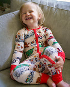 Laughing child sitting on a sofa in Santa Express cream and red zippy
