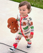 Child standing outdoors in Santa Express zippy while holding a gingerbread toy