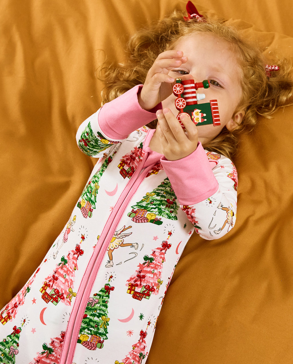 Close view of a child holding a toy train in the Snuggle Sparkle romper.