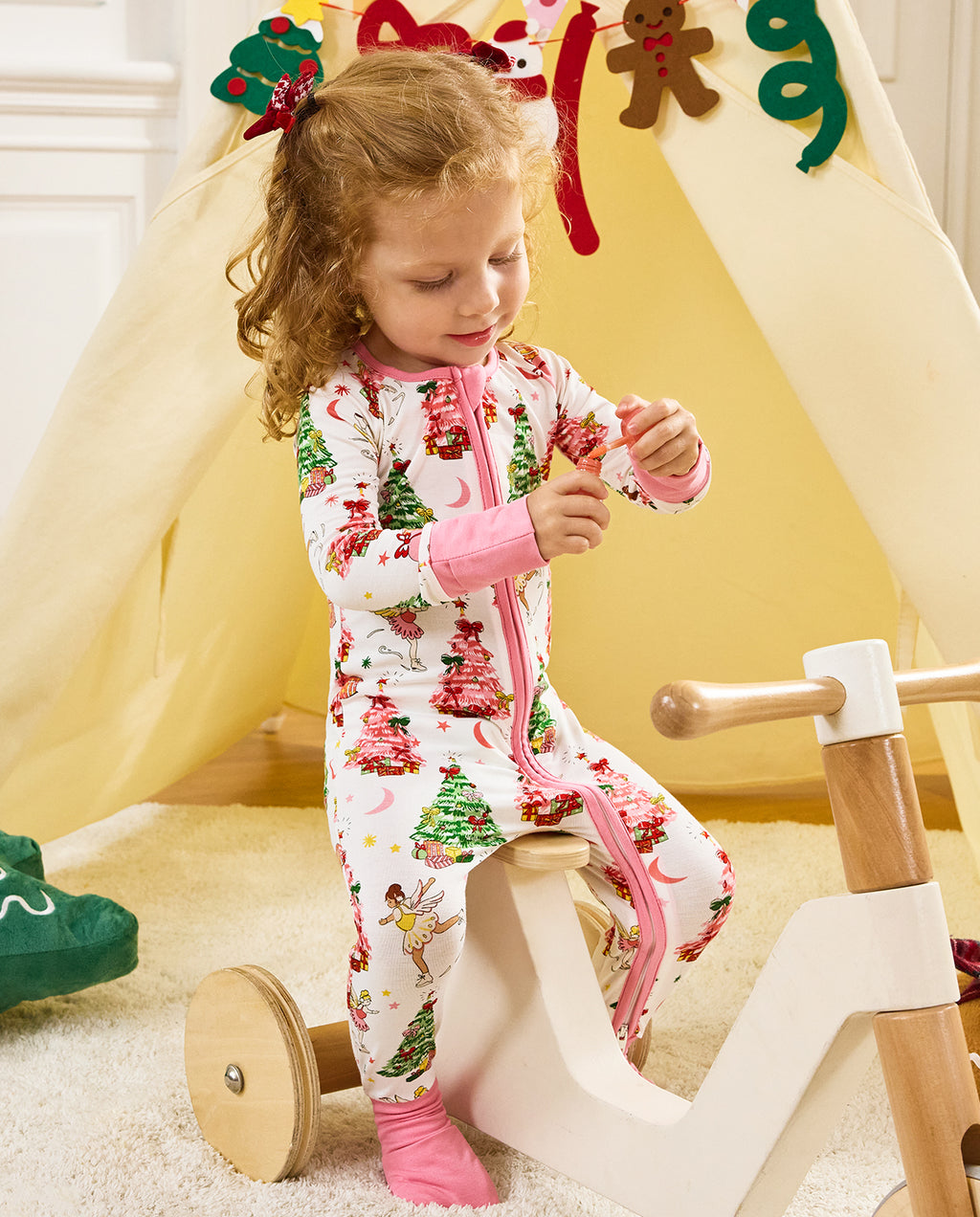 Child seated on a wooden tricycle in the Snuggle Sparkle romper.