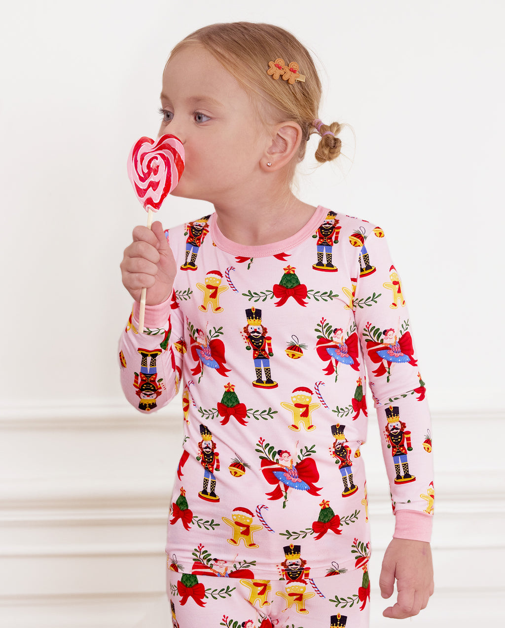 Child holding a swirl lollipop in the light pink Sugarplum Wishes long-sleeve top.