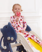 Child seated on a slide holding a lollipop in the Sugarplum Wishes two-piece set.