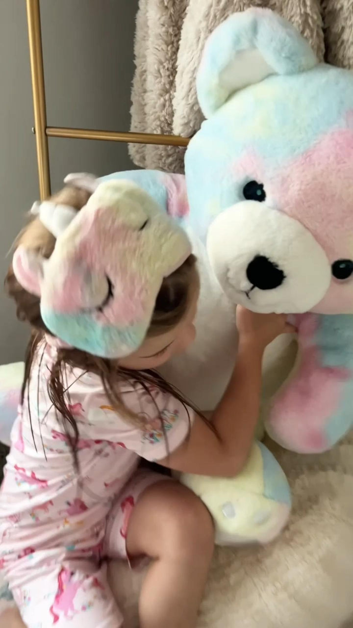 A child in pink unicorn-print Babee Reshinee pajamas with a plush unicorn.
