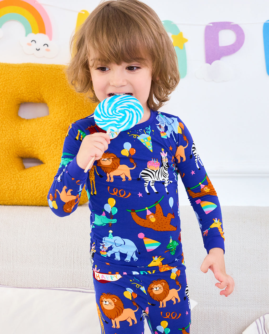 Child holding a lollipop in Birthday Safari pajamas