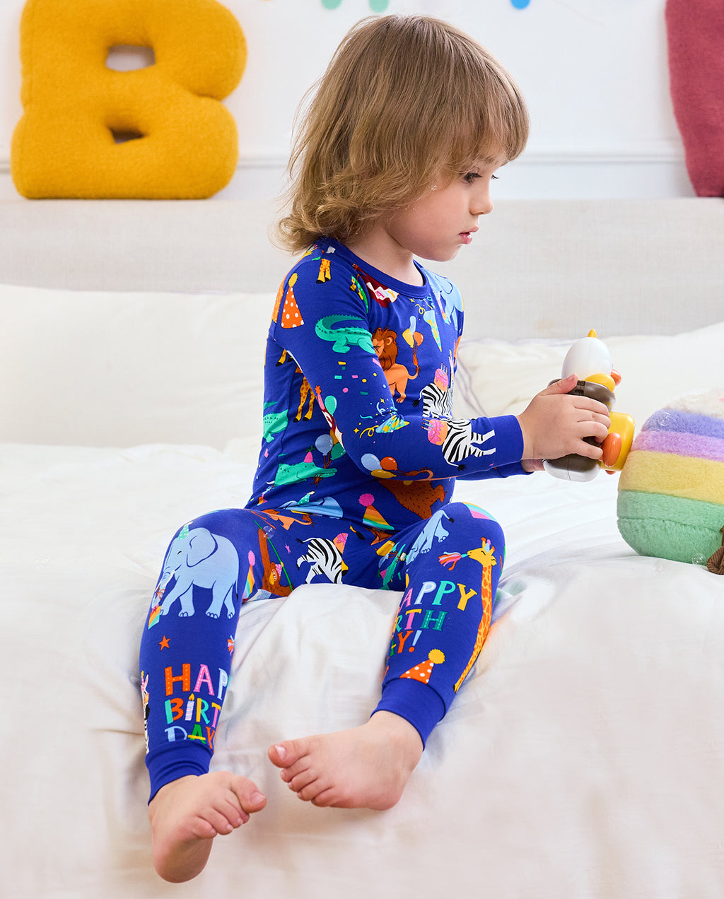 Child seated on a bed in Birthday Safari pajamas