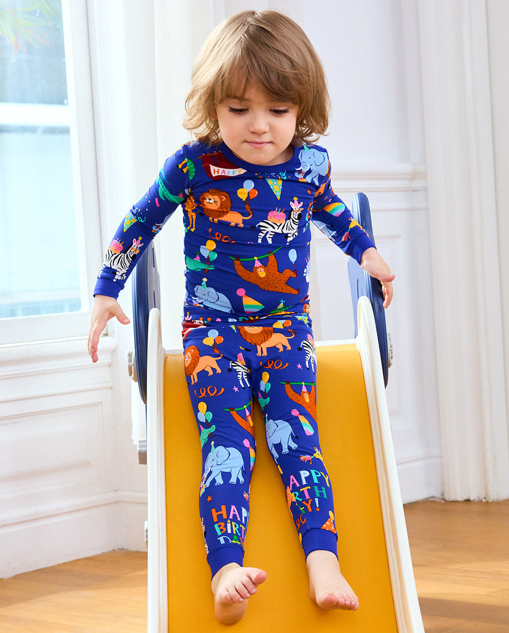 Child playing on a wooden toy in Birthday Safari pajamas