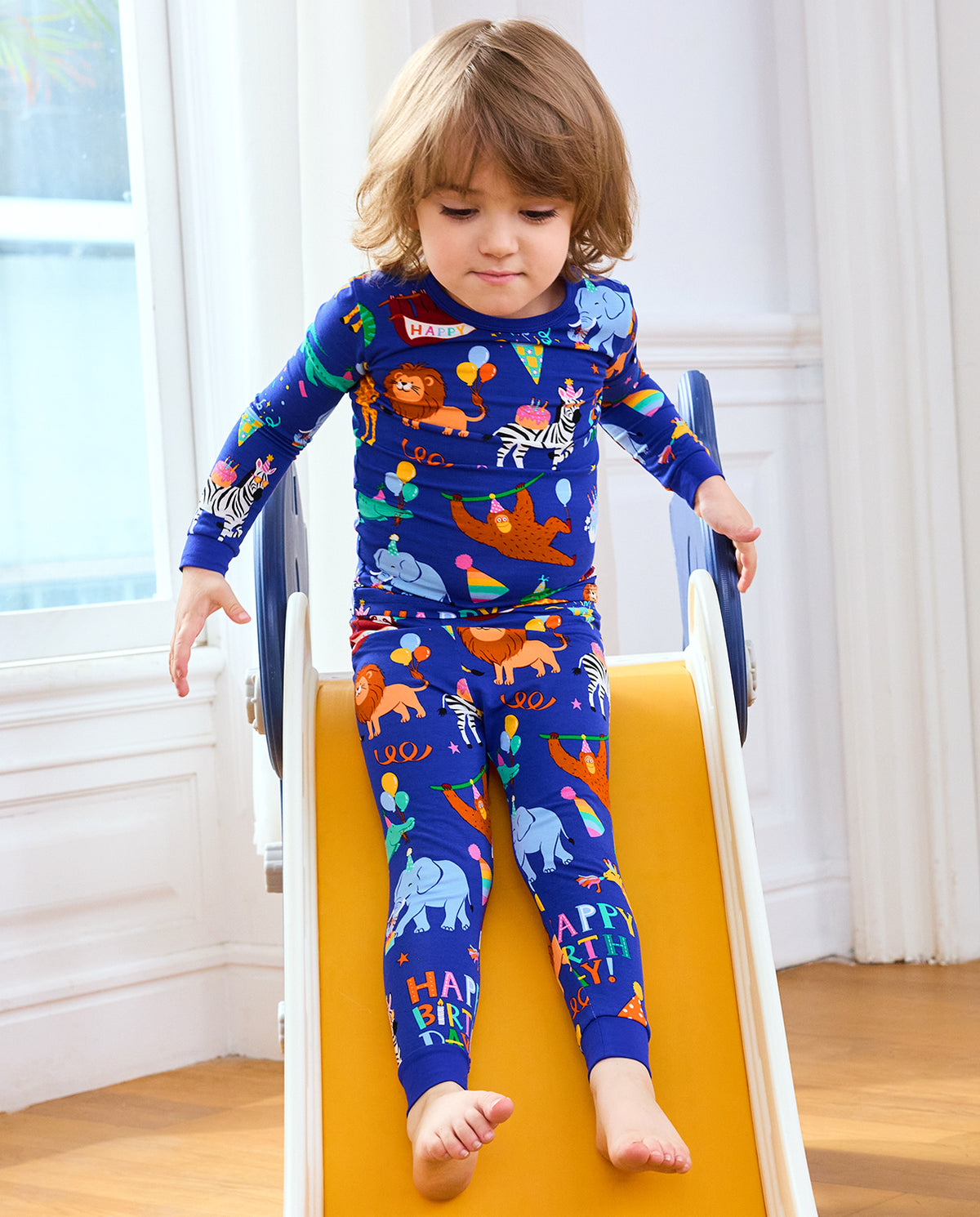 Child playing on a wooden toy in Birthday Safari pajamas