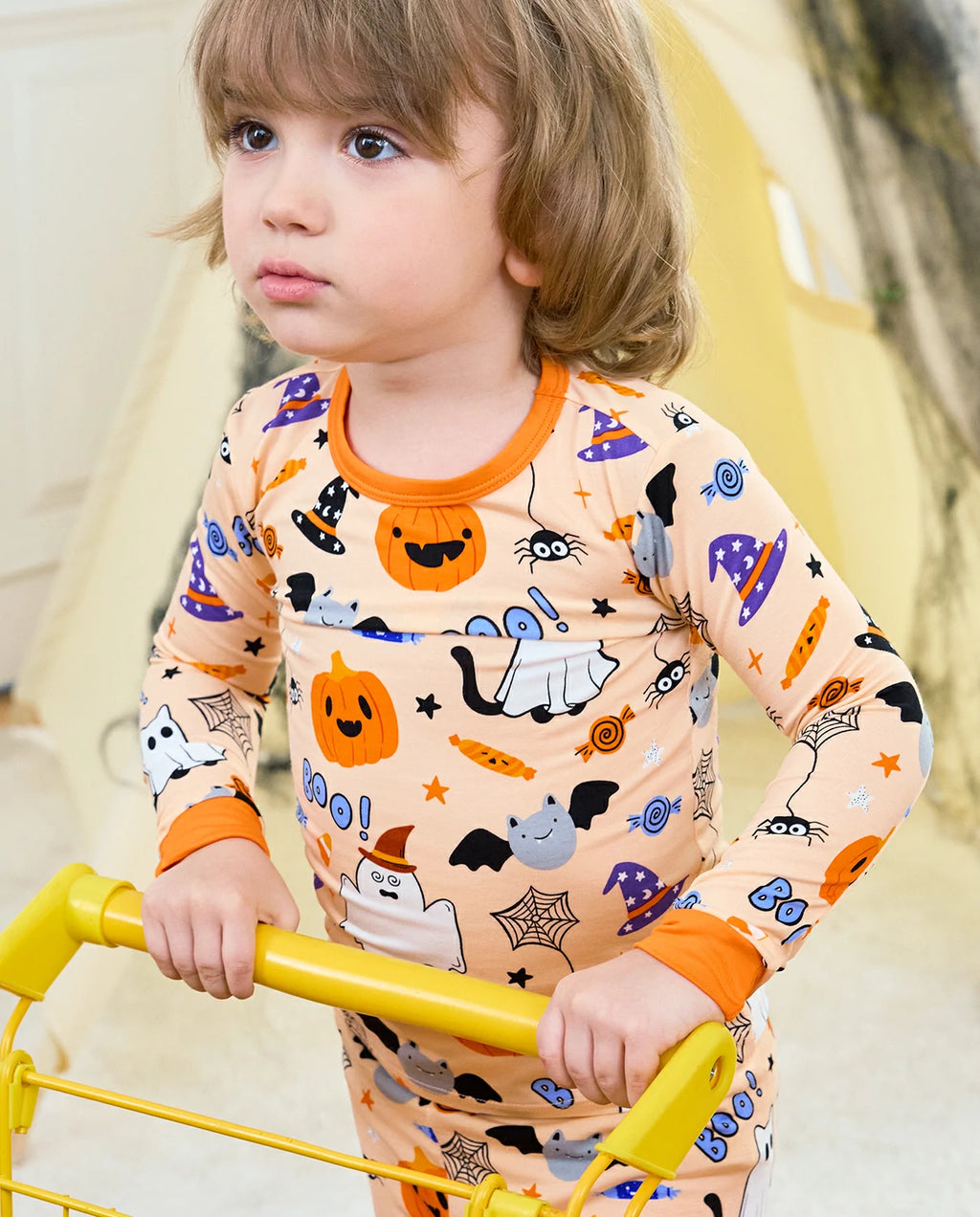Boo Treats Long Two-Piece Pajama Set - child wearing the pajamas while holding a yellow play bar