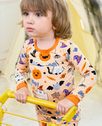 Boo Treats Long Two-Piece Pajama Set - child wearing the pajamas while holding a yellow play bar