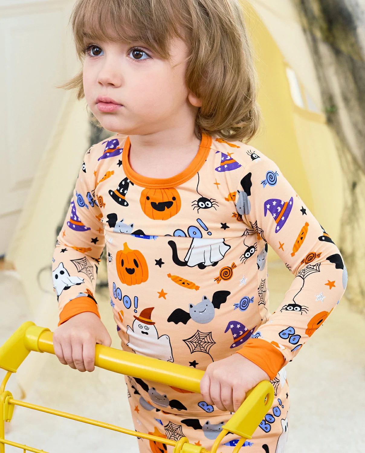 Boo Treats Long Two-Piece Pajama Set - child wearing the pajamas while holding a yellow play bar