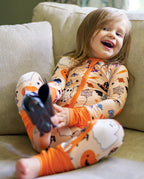 Child smiling on a couch in Boo Treats Bamboo Zippy with Halloween ghost and pumpkin print