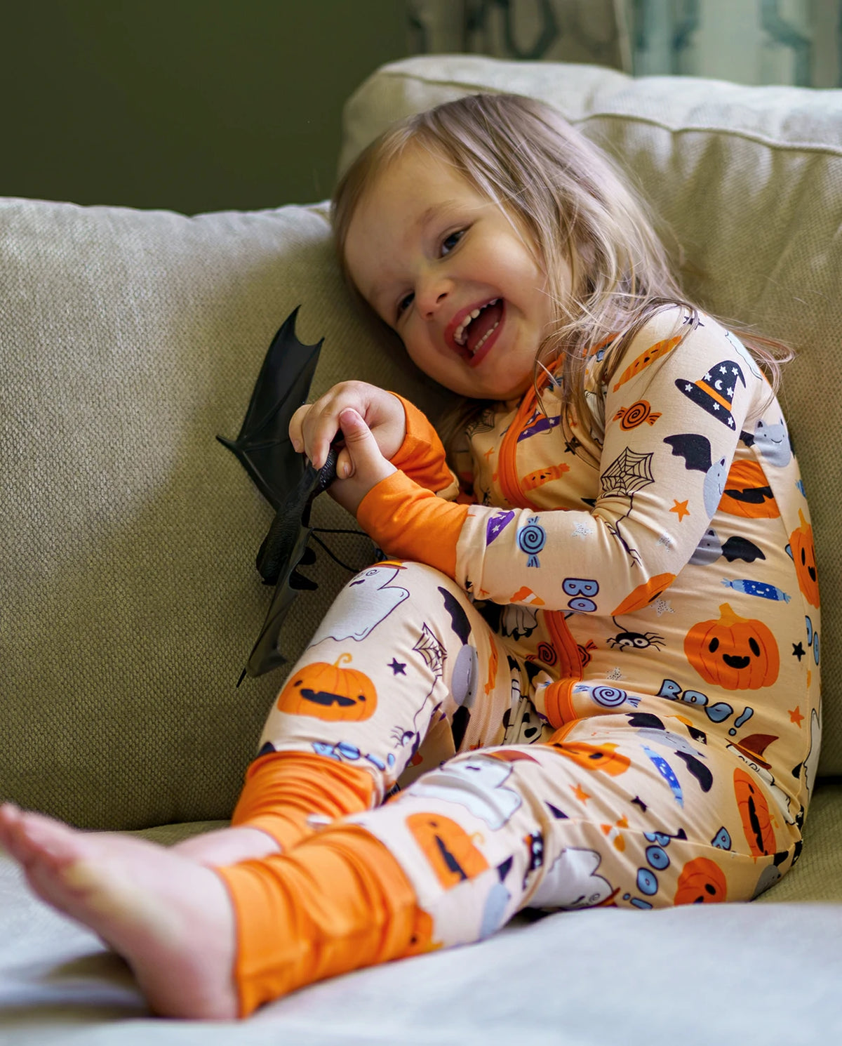 Child laughing in Boo Treats Bamboo Zippy while holding a black bat toy