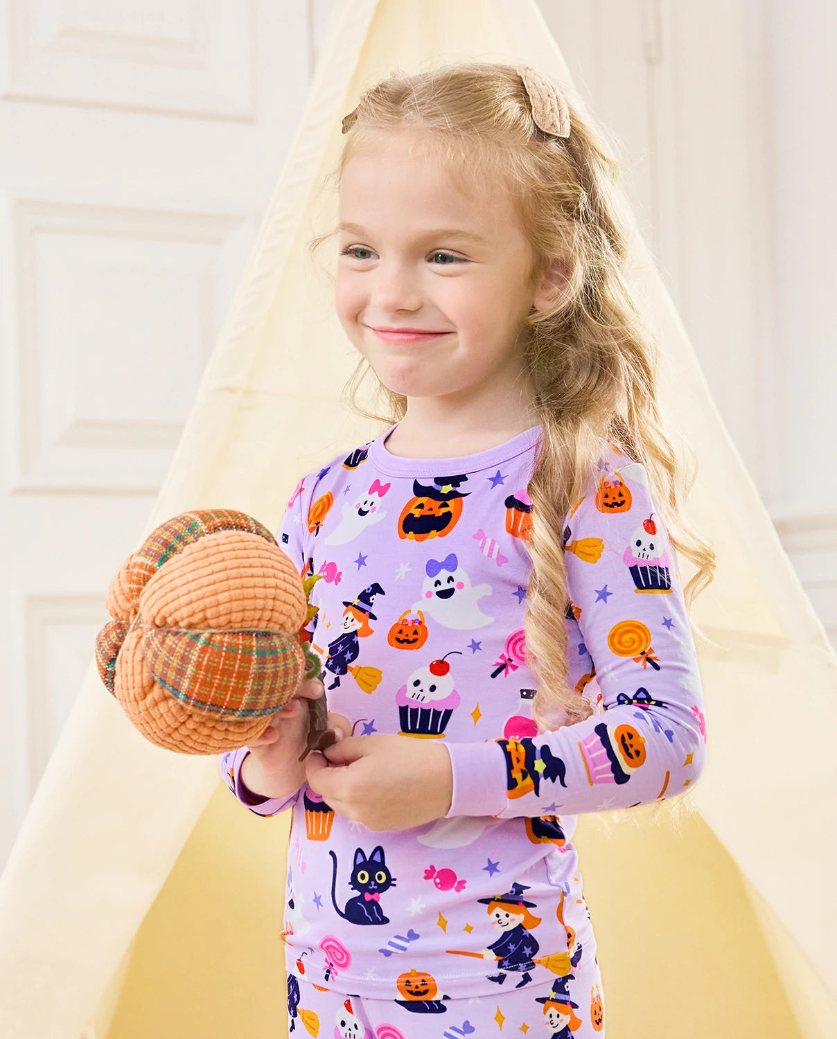 Candy Boo Long Two-Piece Pajama Set - child wearing the purple Halloween pajamas while holding a plush pumpkin