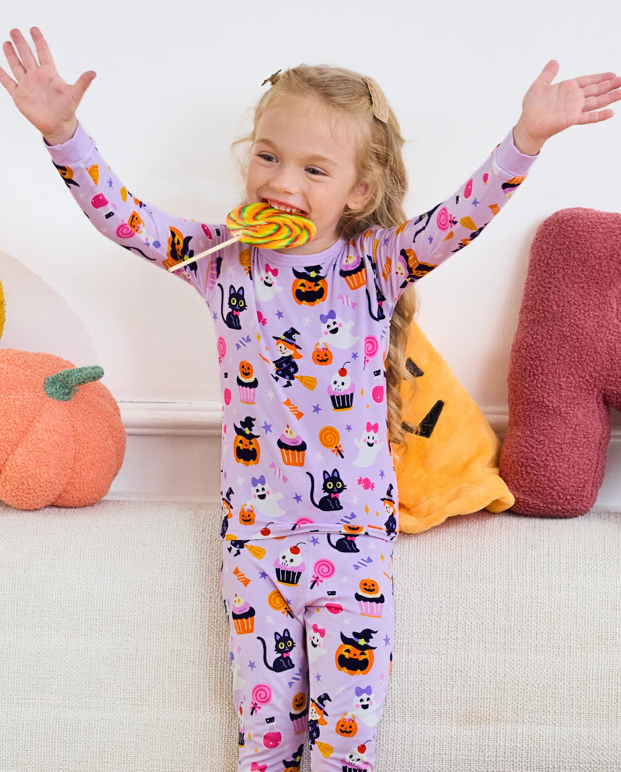 Candy Boo Long Two-Piece Pajama Set - child wearing the pajamas with arms raised and a lollipop