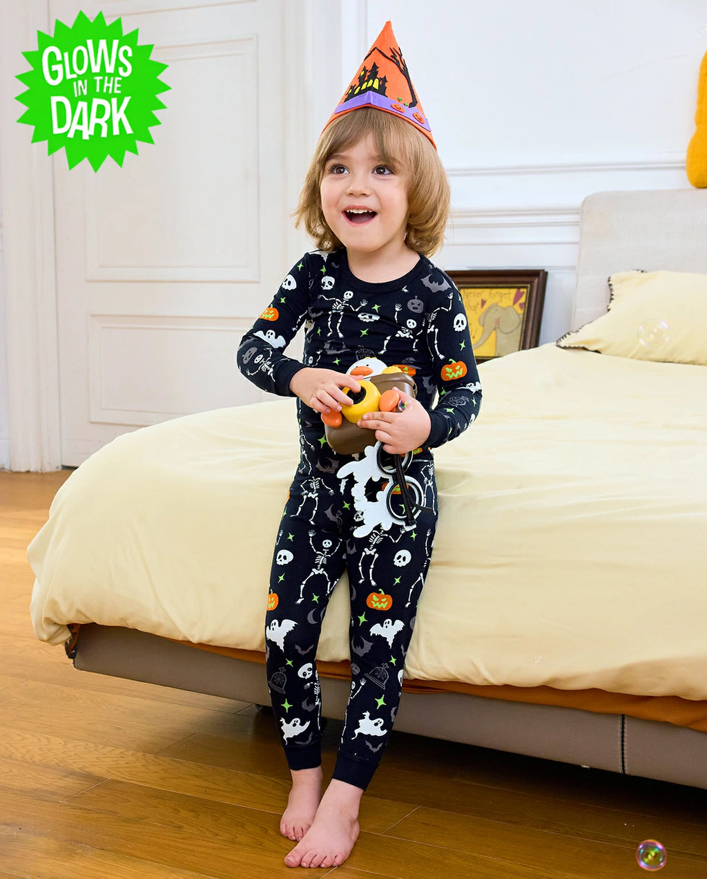 Dark Disco Long Two-Piece Pajama Set - child wearing the glow-print pajamas with a witch hat and pumpkin toy