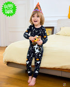 Dark Disco Long Two-Piece Pajama Set - child wearing the glow-print pajamas with a witch hat and pumpkin toy