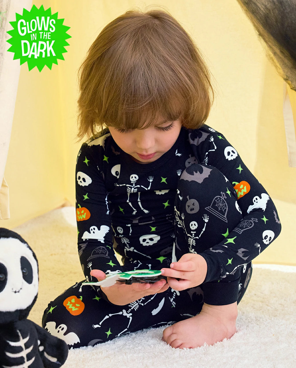 Dark Disco Long Two-Piece Pajama Set - child wearing the glow-print pajamas while seated with a toy