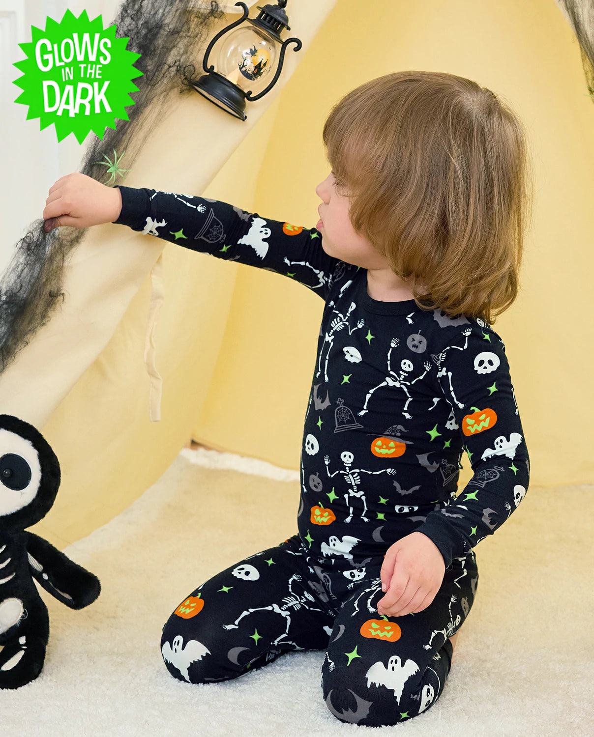 Dark Disco Long Two-Piece Pajama Set - child wearing the glow-print pajamas while seated and reaching