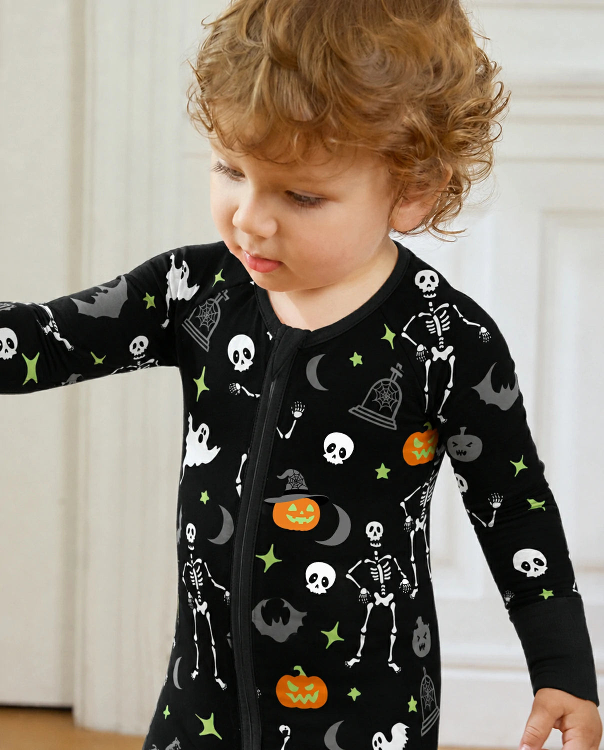 Child wearing Dark Disco Bamboo Zippy with black Halloween skeleton and ghost print indoors