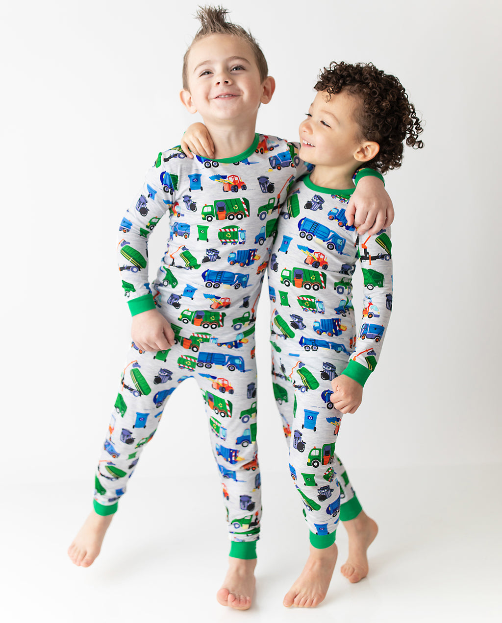 Two children standing in Garbage Squad truck-print pajamas