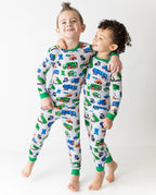 Two children standing in Garbage Squad truck-print pajamas