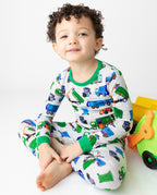Child seated with toy trucks in Garbage Squad pajamas