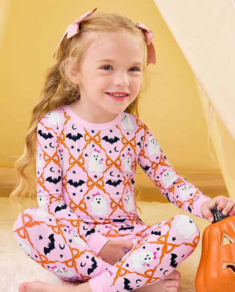 Ghost Bows Long Two-Piece Pajama Set - child wearing the ghost-and-bow pajamas while seated with a pumpkin bucket